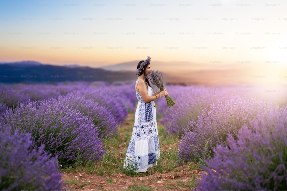 Young woman enjoying the view and the sunlight on her face on a rural flower field with lavender blossoms. High quality photo