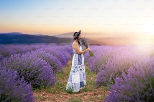 Young woman enjoying the view and the sunlight on her face on a rural flower field with lavender blossoms. High quality photo