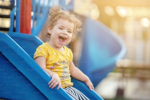 Niño pequeño jugando en el patio de recreo al aire libre en verano.Pequeño niño jugando en el patio de recreo al aire libre en verano.