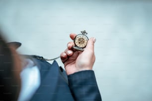 El hombre sostiene y revisa su clásico reloj de bolsillo. Concepto vintage y clásico