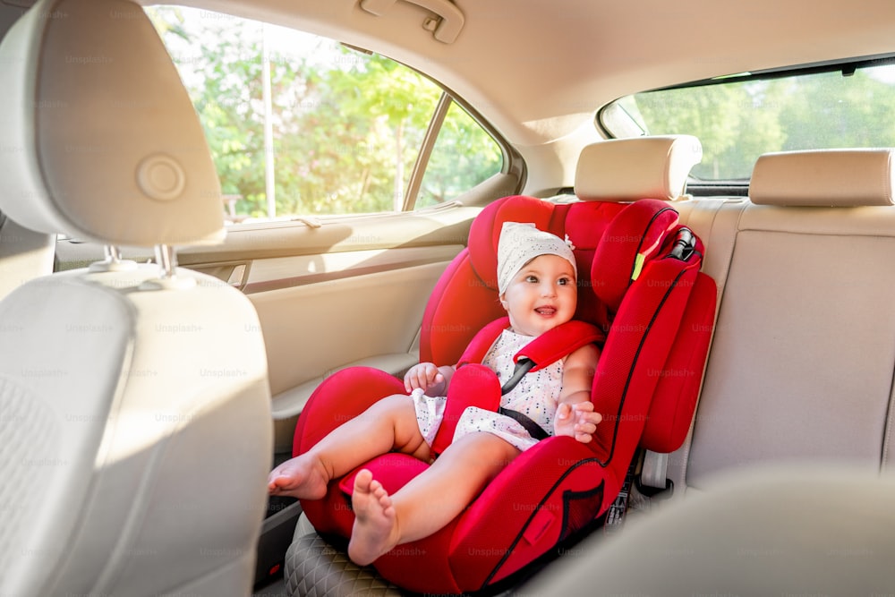 Baby is traveling safe in car on red seat