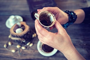여자는 머그잔을 들고 전통적인 터키 커피 컵으로 운세를 말한다