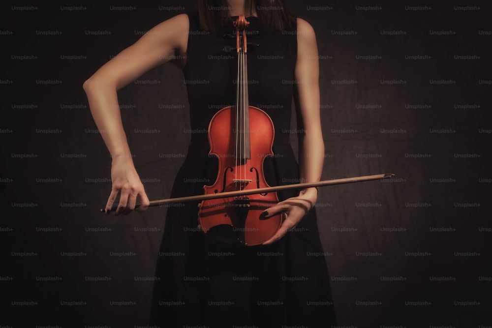 mãos da mulher violinista que joga violiln no fundo preto