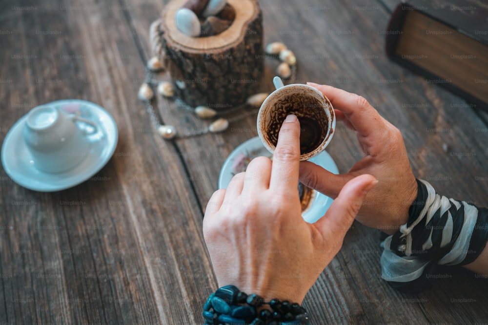여자는 머그잔을 들고 전통적인 터키 커피 컵으로 운세를 말한다
