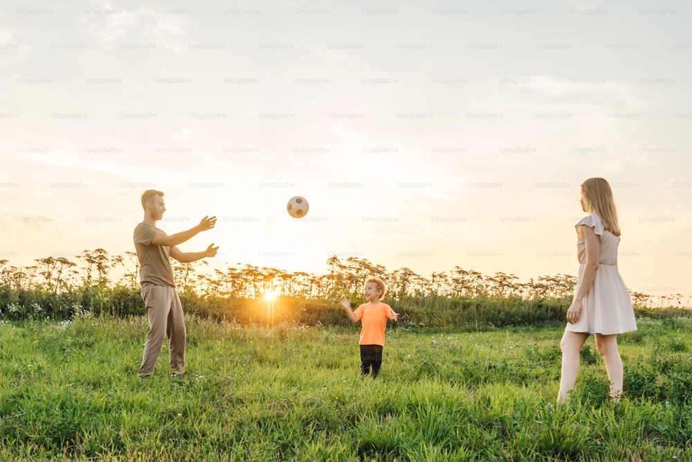 happy young family play with ball outdoor on a summer day, sunset light background.