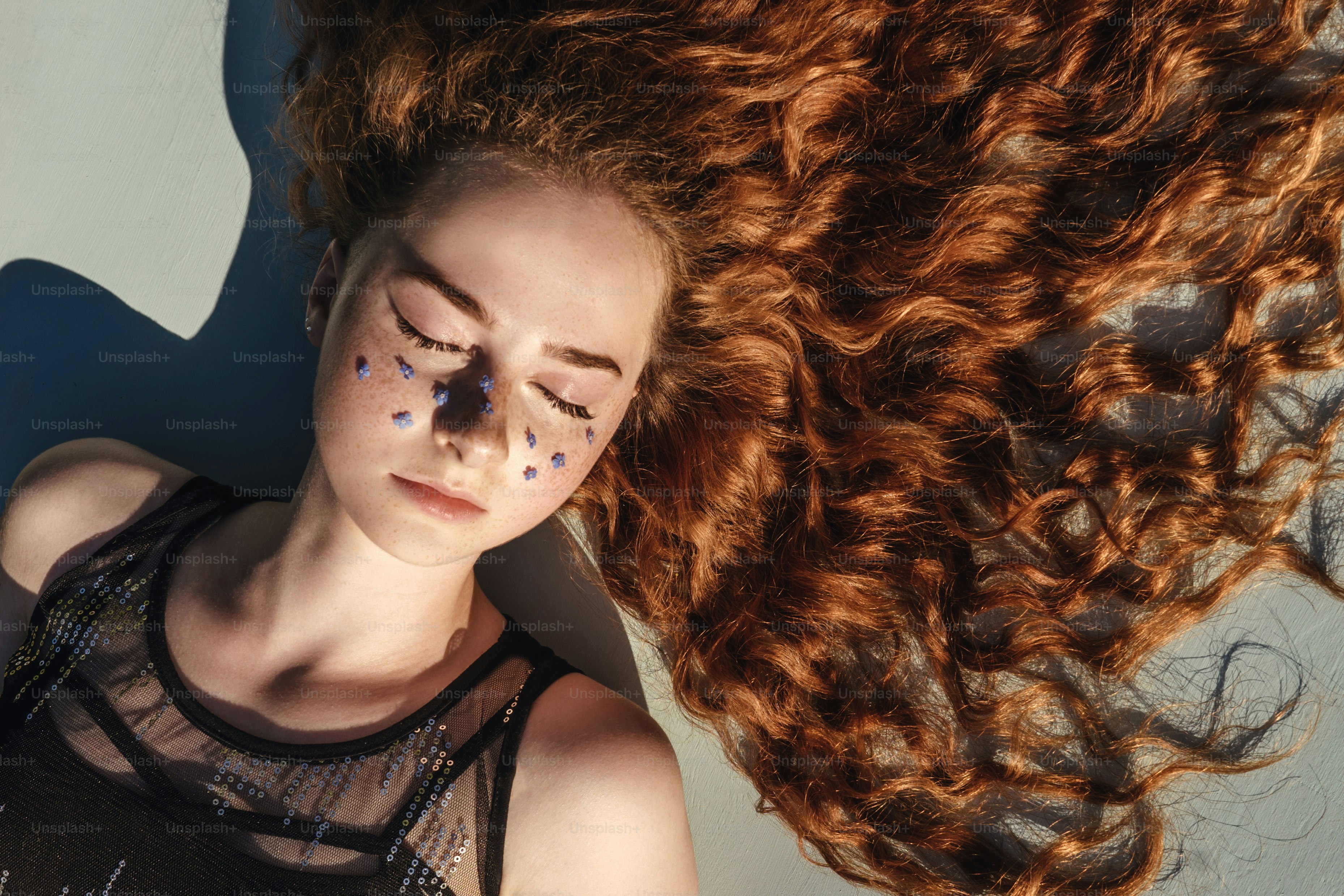 Close up portrait of young ginger curly girl with flowers in hair above ...