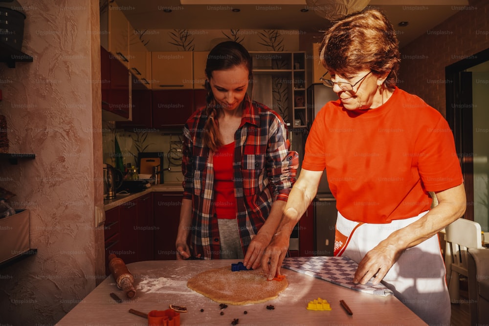 Mujer joven y madre mayor cocinando galletas con ropa roja.
