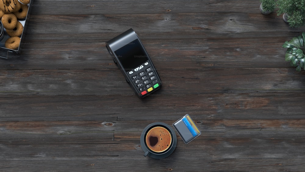 a cell phone sitting on top of a wooden table next to a cup of coffee