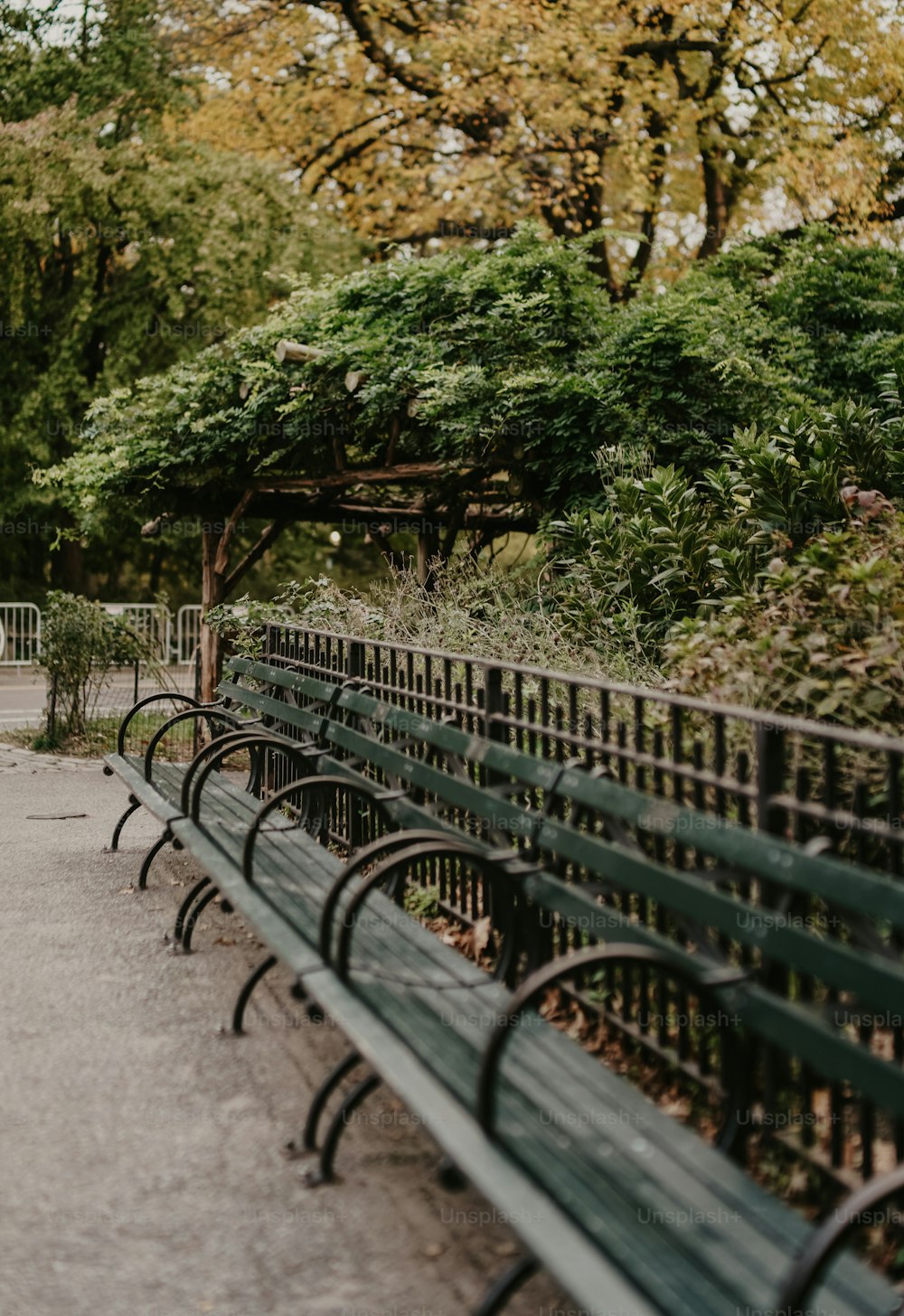 a row of green park benches sitting next to each other