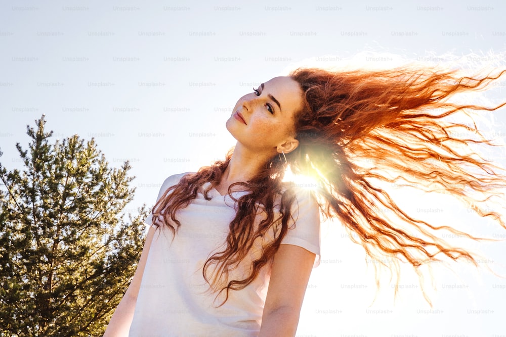 Young happy woman with long curly hair in sunshine. Country life. White t-shirt.