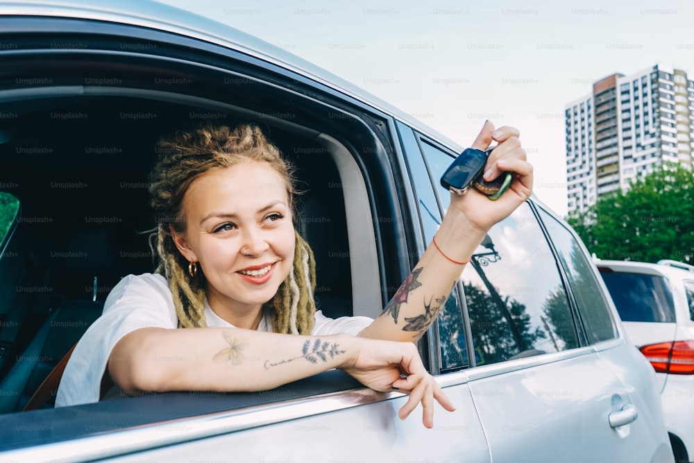 Glückliche lächelnde Frau mit Autoschlüssel. Frau mit Dreadlocks.