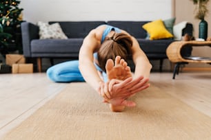 Portrait of young woman practicing yoga indoor. Woman practice janu sirsasana at home.