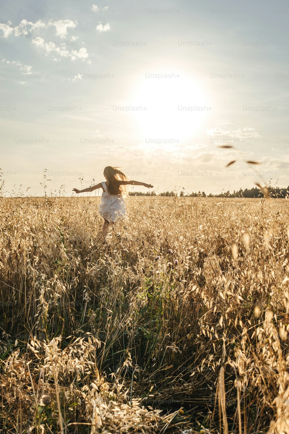 Menina correndo no prado ao longe. Luz do pôr-do-sol, espaço de cópia.