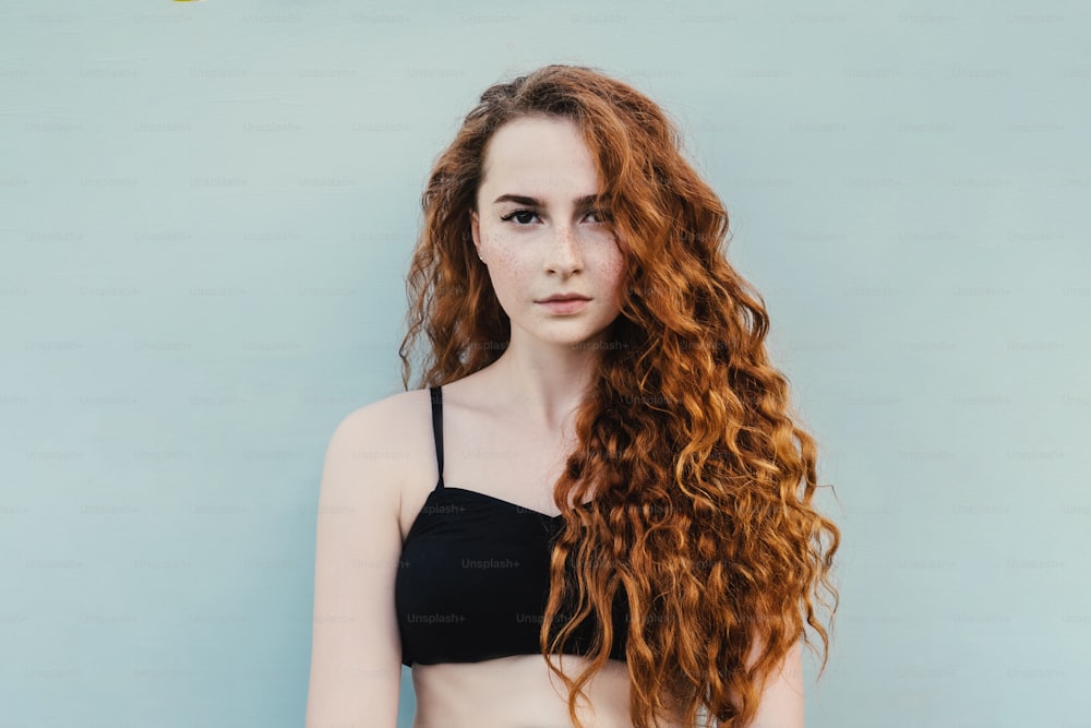 Portrait of ginger woman with red curly hair on blue background.
