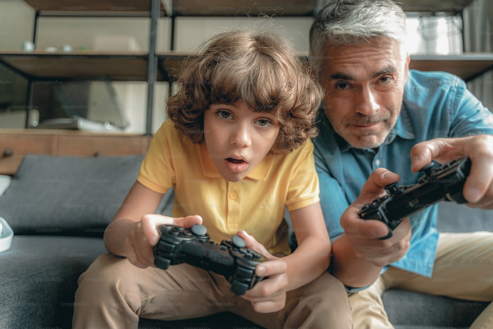 Wondered little boy sitting near father and playing in video games at home
