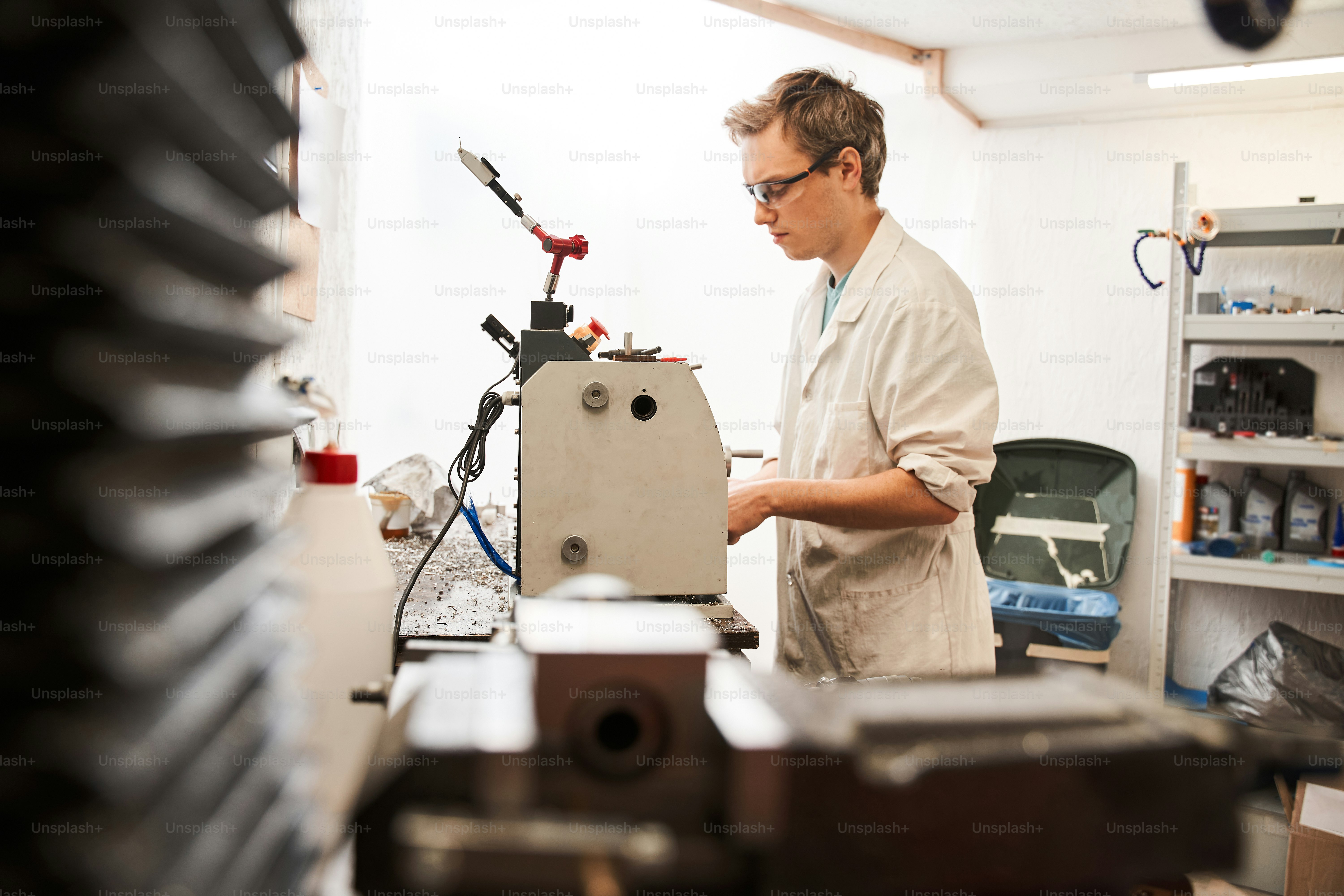Full length view of the man engineer standing at the special machine and working while developing prothesis artificial limbs. Engineering of the bionic hands concept. Stock photo
