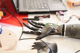 Vue rapprochée de la main bionique noire posée sur la table pendant que les travailleurs l’inspectent pendant le développement au laboratoire d’ingénieurs. Photo d’archives