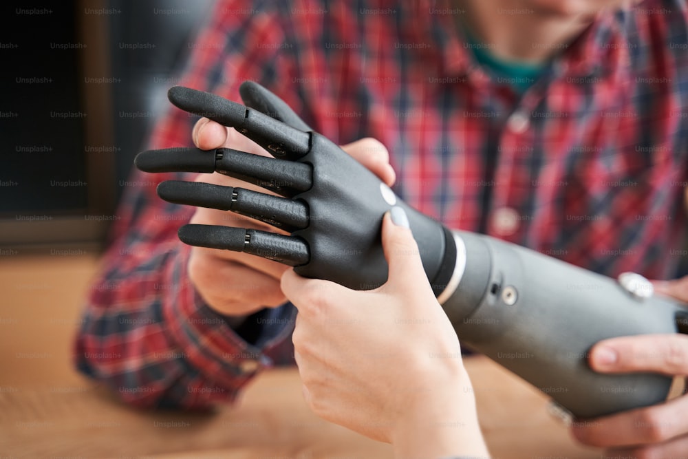 Close up view of the engineer showing a new artificial limb for his client or patient. Woman touching to the artificial limb. Engineering of the bionic hands concept. Stock photo