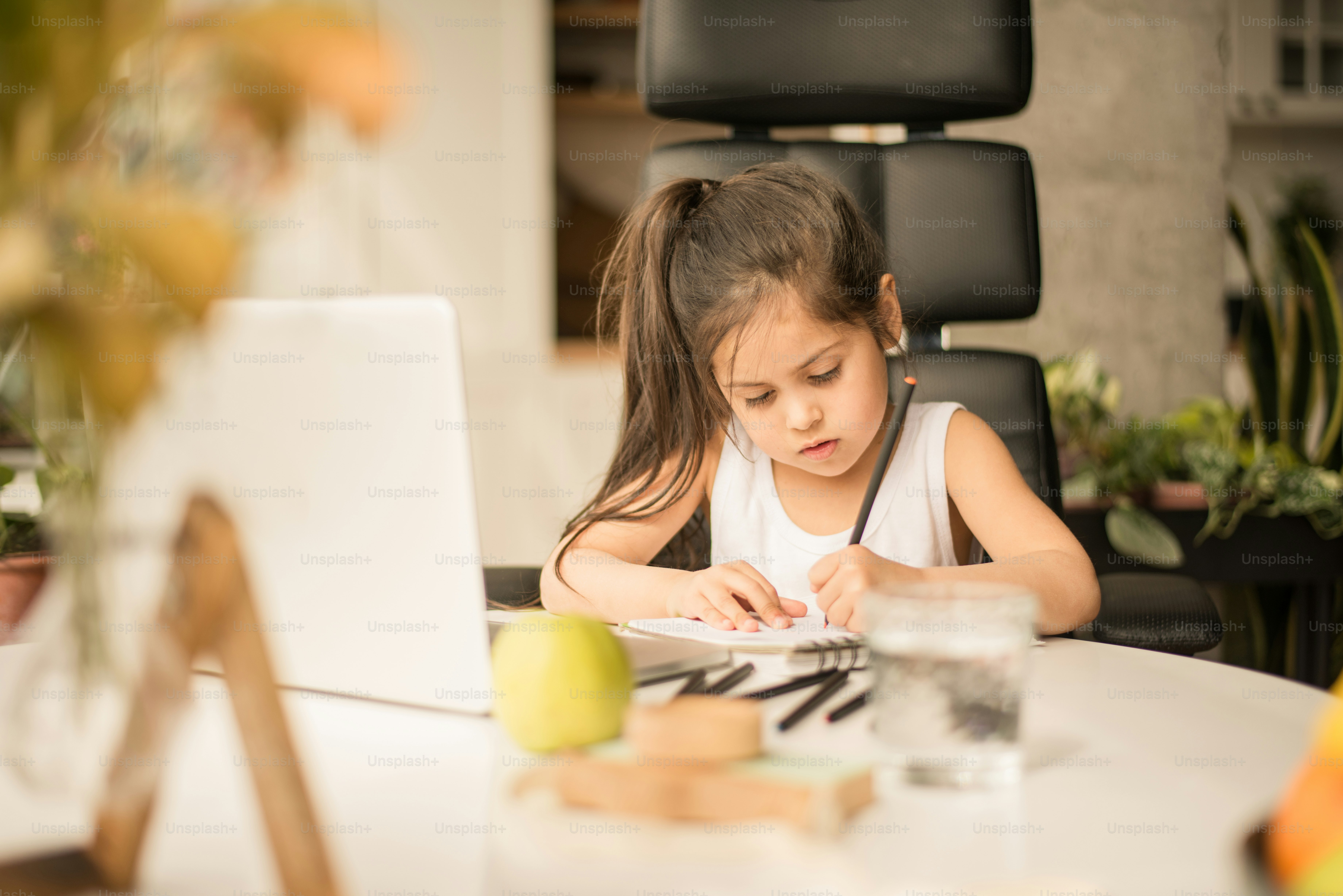Portrait view of the school girl studying online from home and making ...