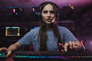 Online streaming. Waist up portrait view of the concentrated female gamer pointing at the button and telling something to subscribers while playing at the game