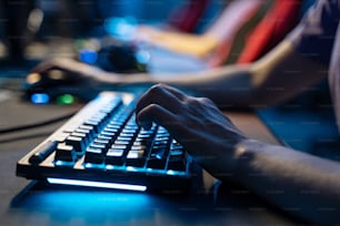 Cropped view of the man holding hands at the computer keyboard while playing at the online game during the streaming. Stock photo
