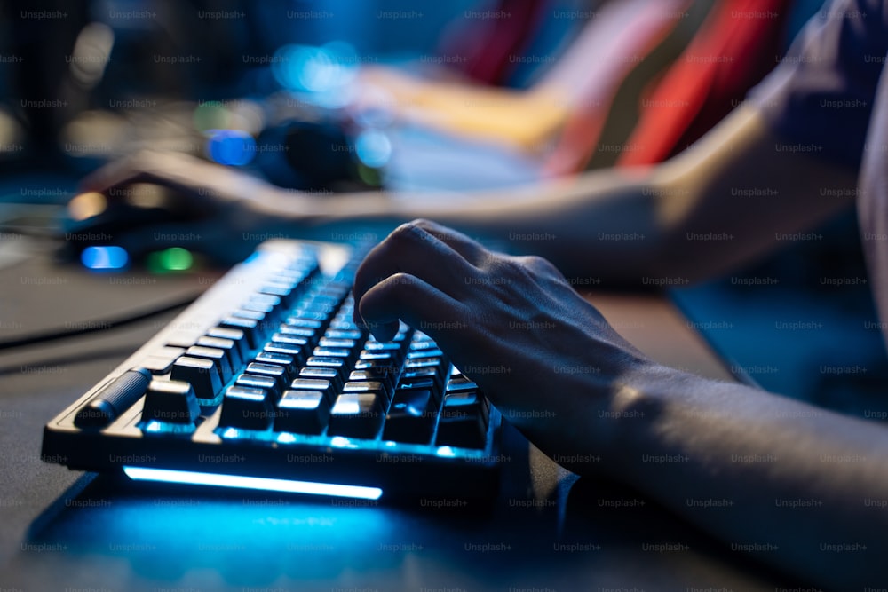 Cropped view of the man holding hands at the computer keyboard while playing at the online game during the streaming. Stock photo