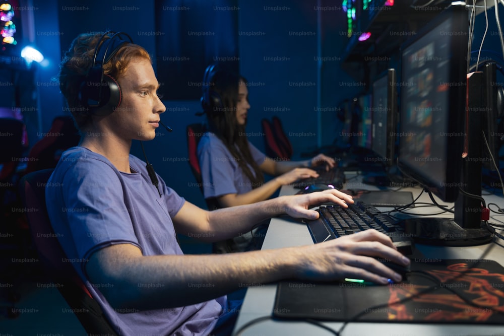 Vielfältiges Team von professionellen Cybersport-Spielern mit Kopfhörern, die an einem globalen eSport-Turnier teilnehmen, Online-Videospiele spielen, Seitenansicht