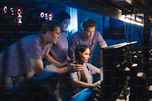 Two guys and girl at the computer club giving support to their female friend during her game. Cybersport concept. Stock photo