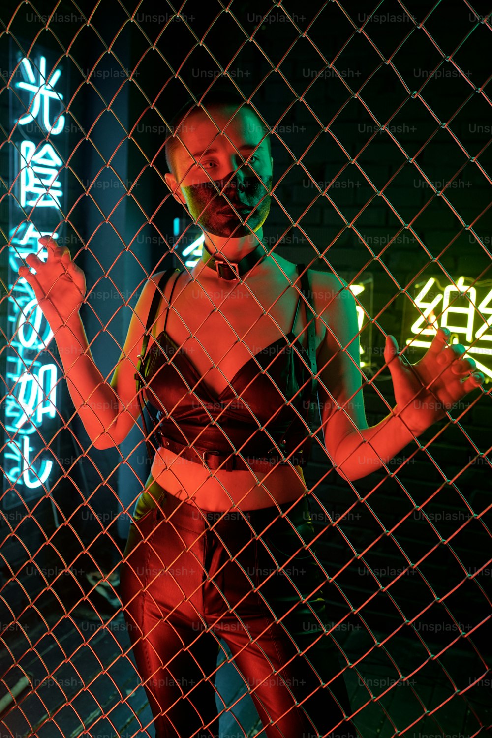 Cyberpunk girl standing in leather costume behind the bars with neon hieroglyphs meaning nirvana and western paradise