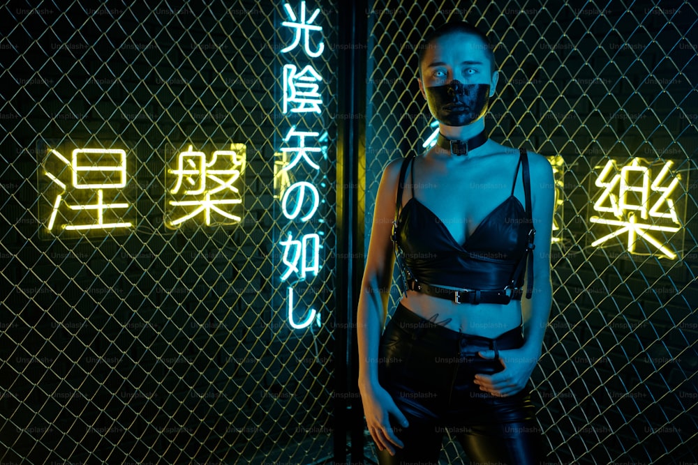 Portrait of cyberpunk woman standing in leather tank top and pants looking at camera with hieroglyphs meaning nirvana and western paradise in the background