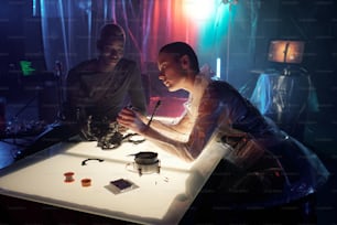 ハッカーの隠れ家でテーブルに座って電子機器を扱う若い異文化の男性と女性のサイバーパンク
