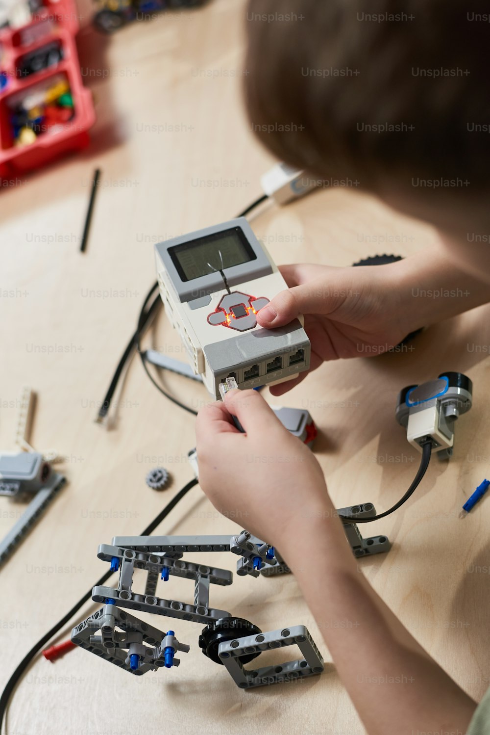 Nahaufnahme eines Jungen, der einen Roboterkonstrukteur aus Kunststoff baut, der im Robotik-Schulunterricht am Computer programmiert