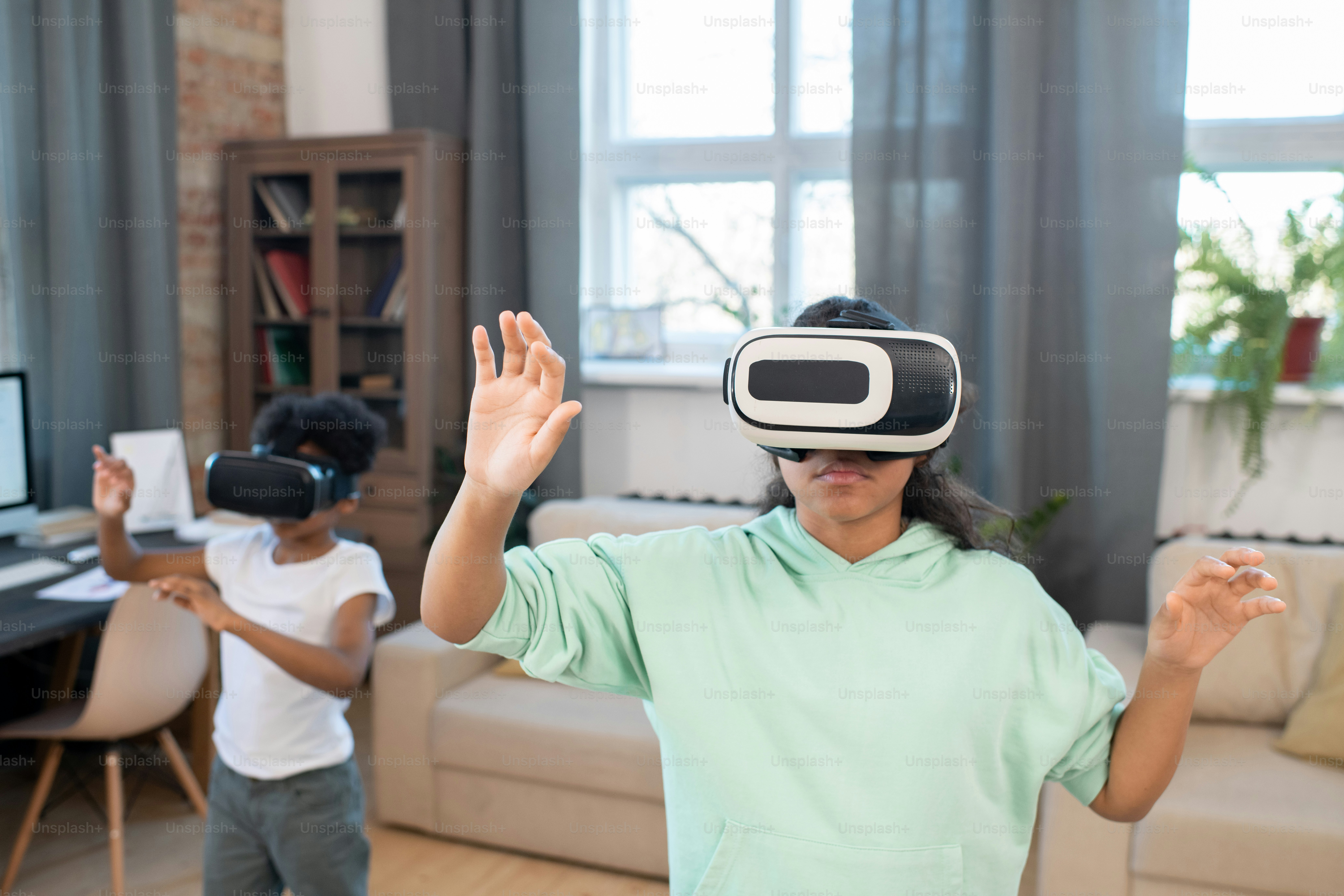 Adoráveis irmãos mestiços em fones de ouvido vr assistindo a vídeos on-line em grande exibição virtual enquanto estão na frente da câmera na sala de estar