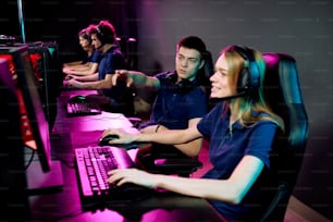 Junger Cyber-Sport-Gamer gibt einem Mädchen mit Kopfhörern Ratschläge, während sie sich auf einen E-Sport-Wettbewerb vorbereiten