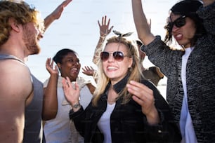 Des amis multiraciaux aiment danser sur la plage par une soirée ensoleillée