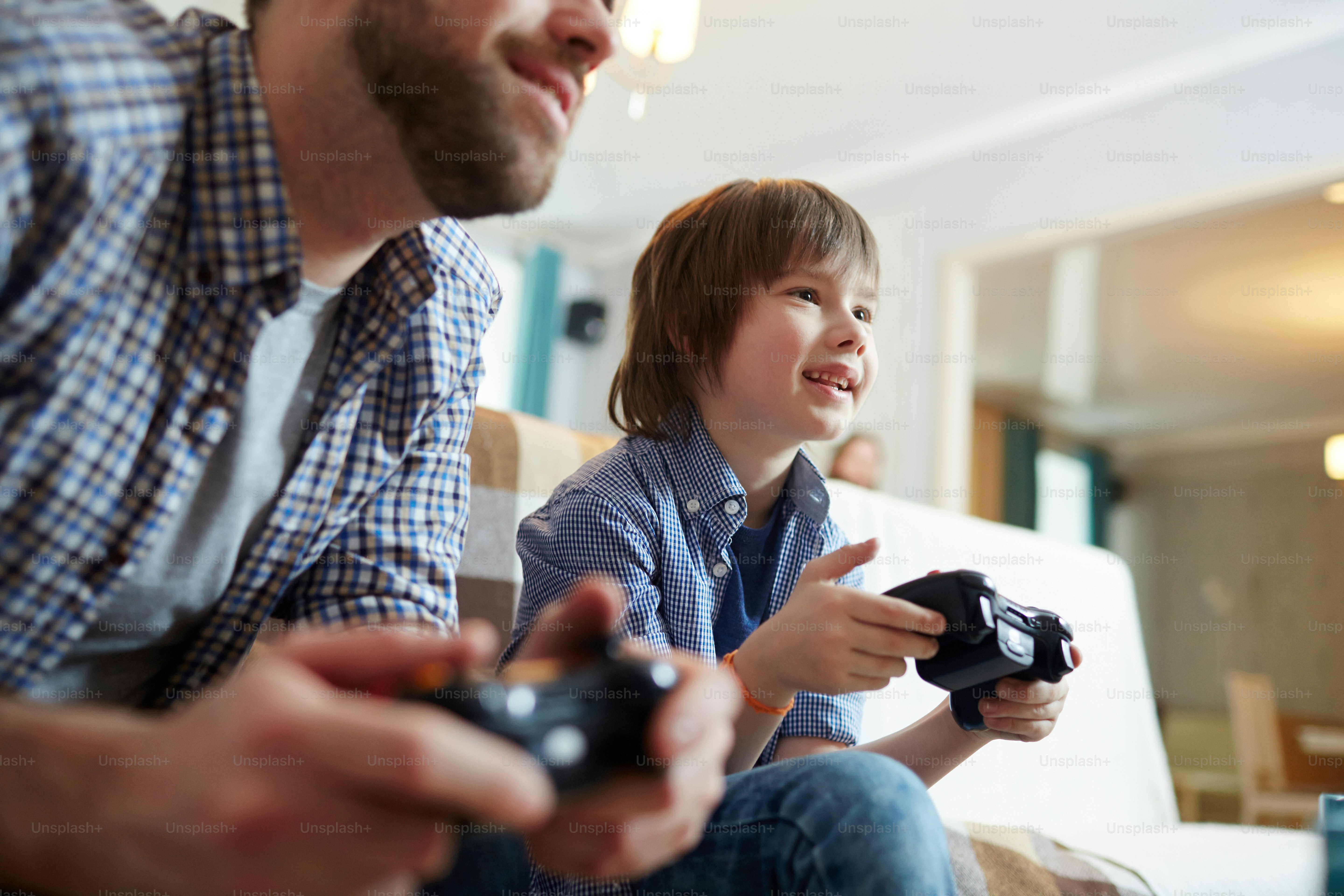 Happy boy with console and his father playing video game at home