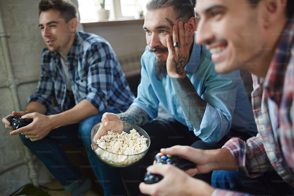 Homme barbu avec des tatouages regardant le jeu vidéo de ses amis