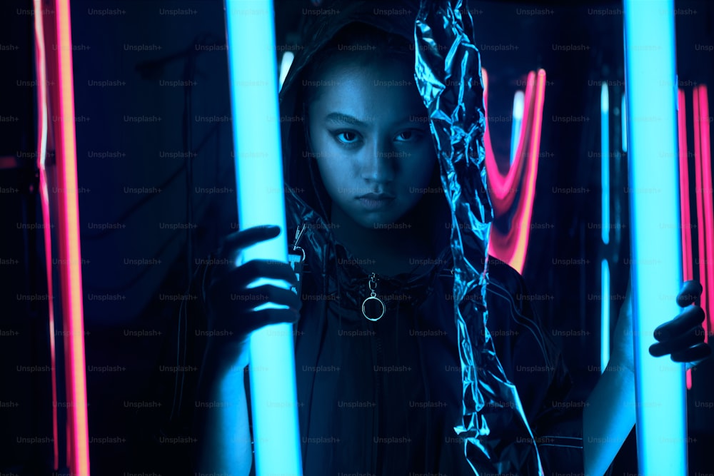 Portrait of young asian teenage girl in red neon light. Cyber, futuristic portrait concept, looking forward