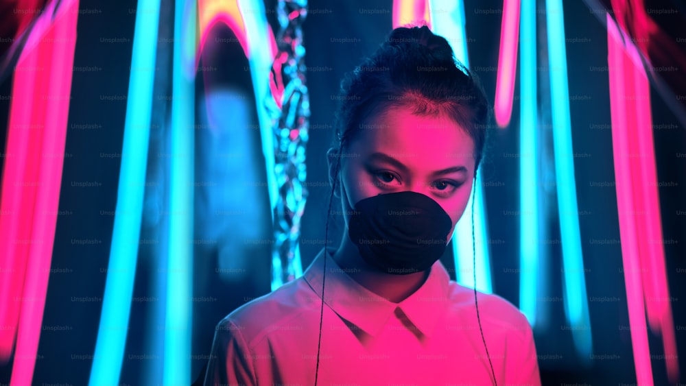 Porträt eines jungen asiatischen Teenager-Mädchens, das eine Maske in lila und blauem Neonlicht trägt. Cyber, futuristisch, Virenschutzkonzept