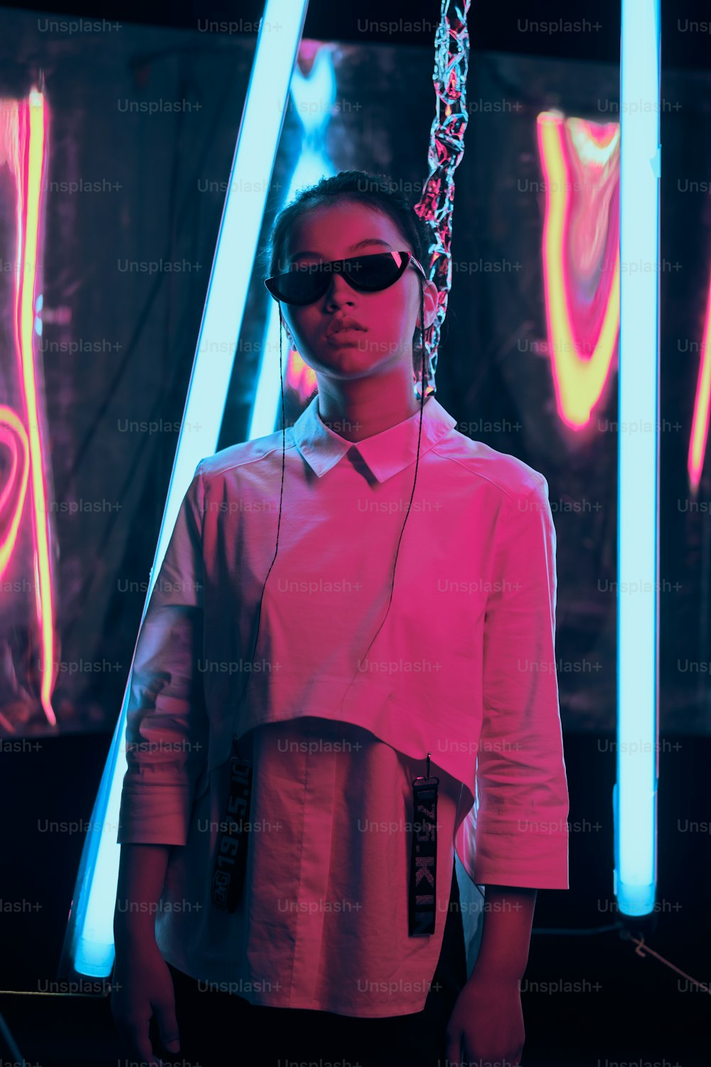 세련된 초승달 모양의 선글라스를 쓴 젊은 아시아 십대 소녀의 초상화, 빨간색과 파란색 네온 불빛. 사이버, 미래 지향적인 초상화 개념