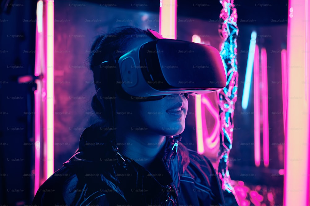 Porträt eines jungen Mädchens mit Virtual-Reality-Brille. Sie ist von Neonlicht umgeben. Virtual-Reality-Point-of-View-Konzept