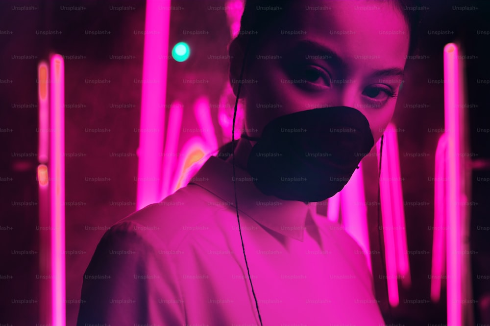 紫色のネオンライトにマスクを着たアジアの若い10代の女の子のポートレート。サイバー、未来、ウイルス対策のコンセプト