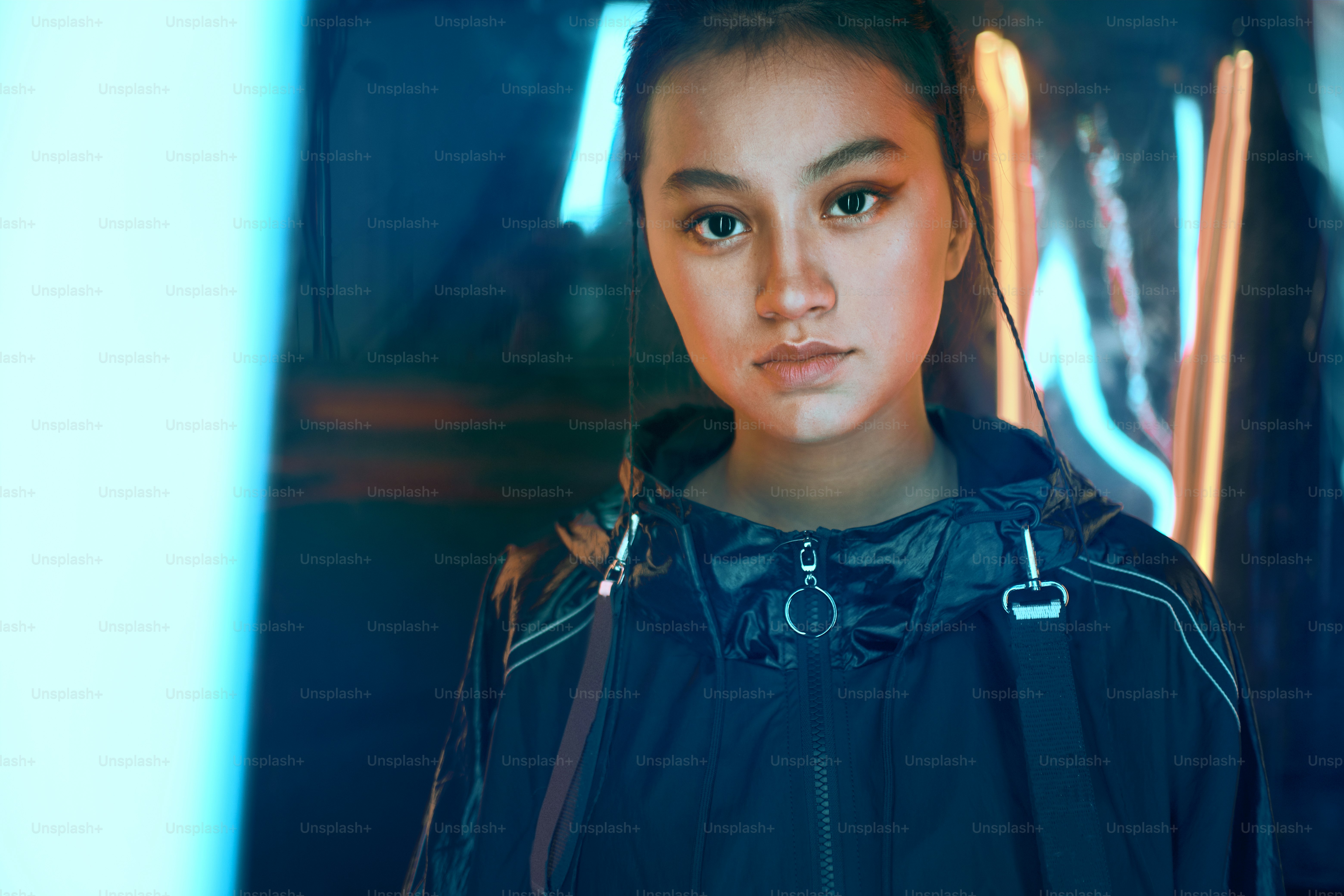 Futuristic portrait of asian teenager in neon light. She is seriour, daring, cyberpunk fashionable girl