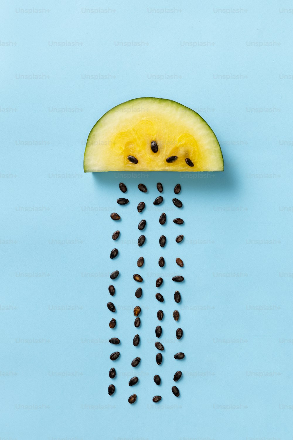 Diseño creativo con rodajas de mango amarillo o sandía de piña con semillas que llueven aisladas sobre fondo azul. Plano laico. Concepto meteorológico. Arte, sabor, salud, anuncio