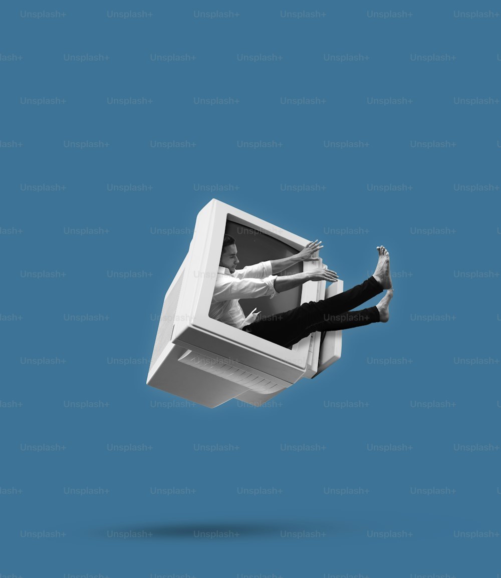 Retro computer monitor draws a man into itself on blue background. Contemporary art collage and modern design. Concept of idea, inspiration, creativity and art. Minimalism, surrealism