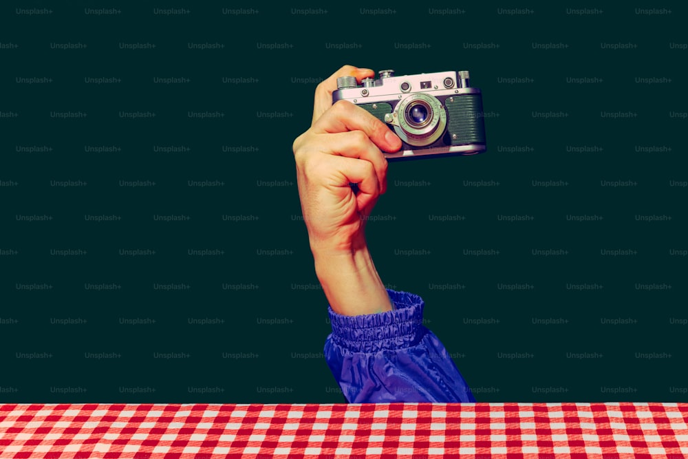 Mach ein Foto. Konzept der Pop-Art-Fotografie. Mit Retro-Gadgets. Menschliche Hand, die eine Fotokamera auf grünem Hintergrund hält. Vintage, Retro 80er, 70er Jahre. Komplementärfarben. Konzept der Erinnerung, Nostalgie