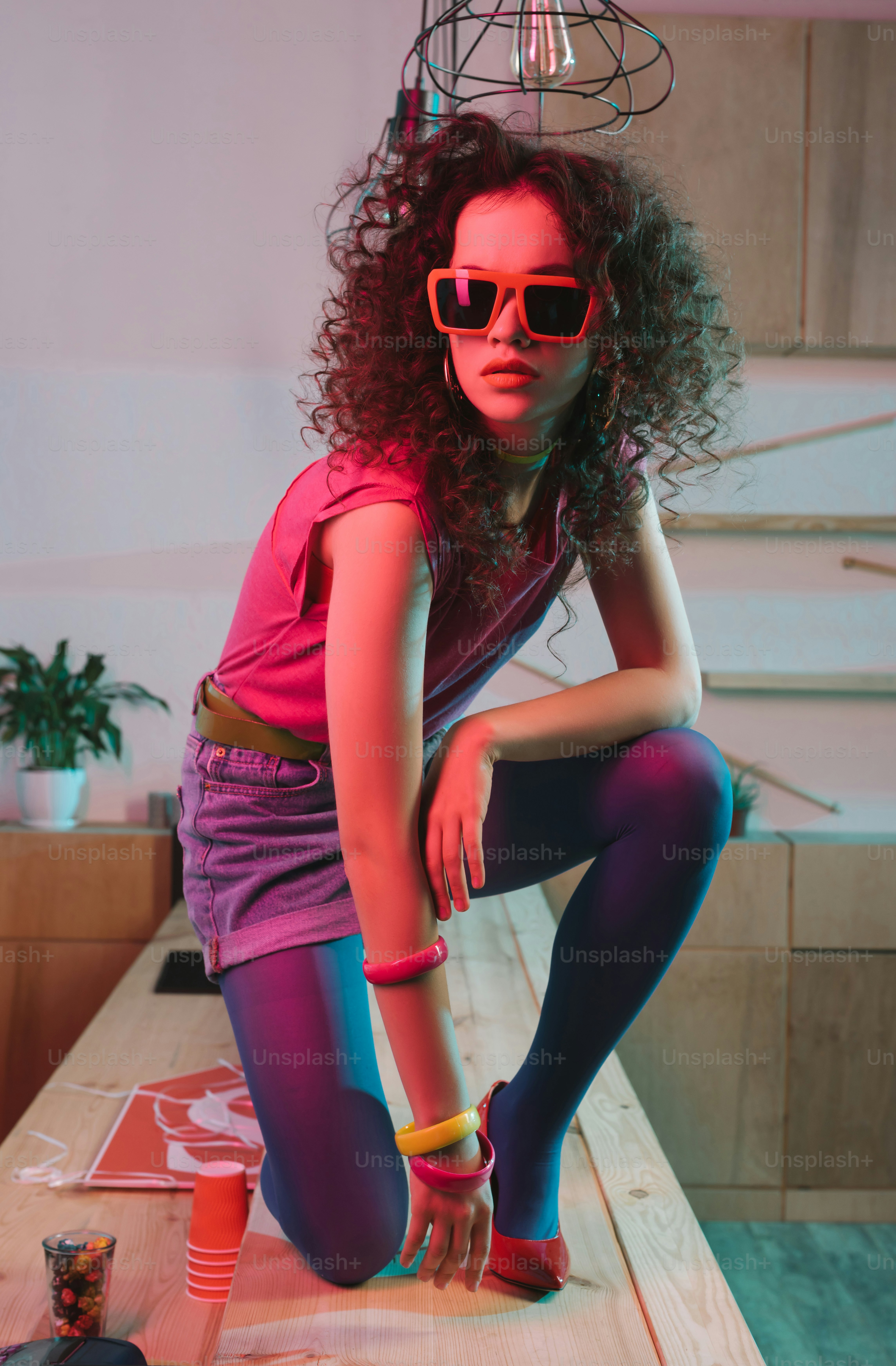 fashionable woman in sunglasses posing on wooden counter in bar