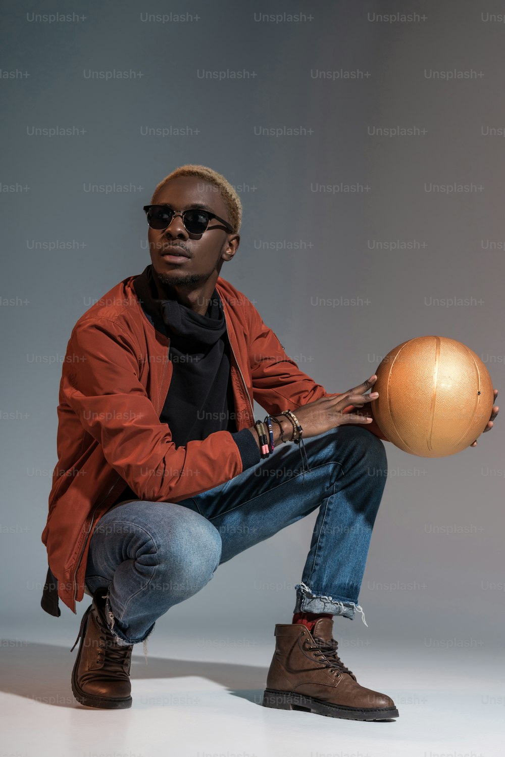 Stylish young african american man sitting with basketball ball in hands