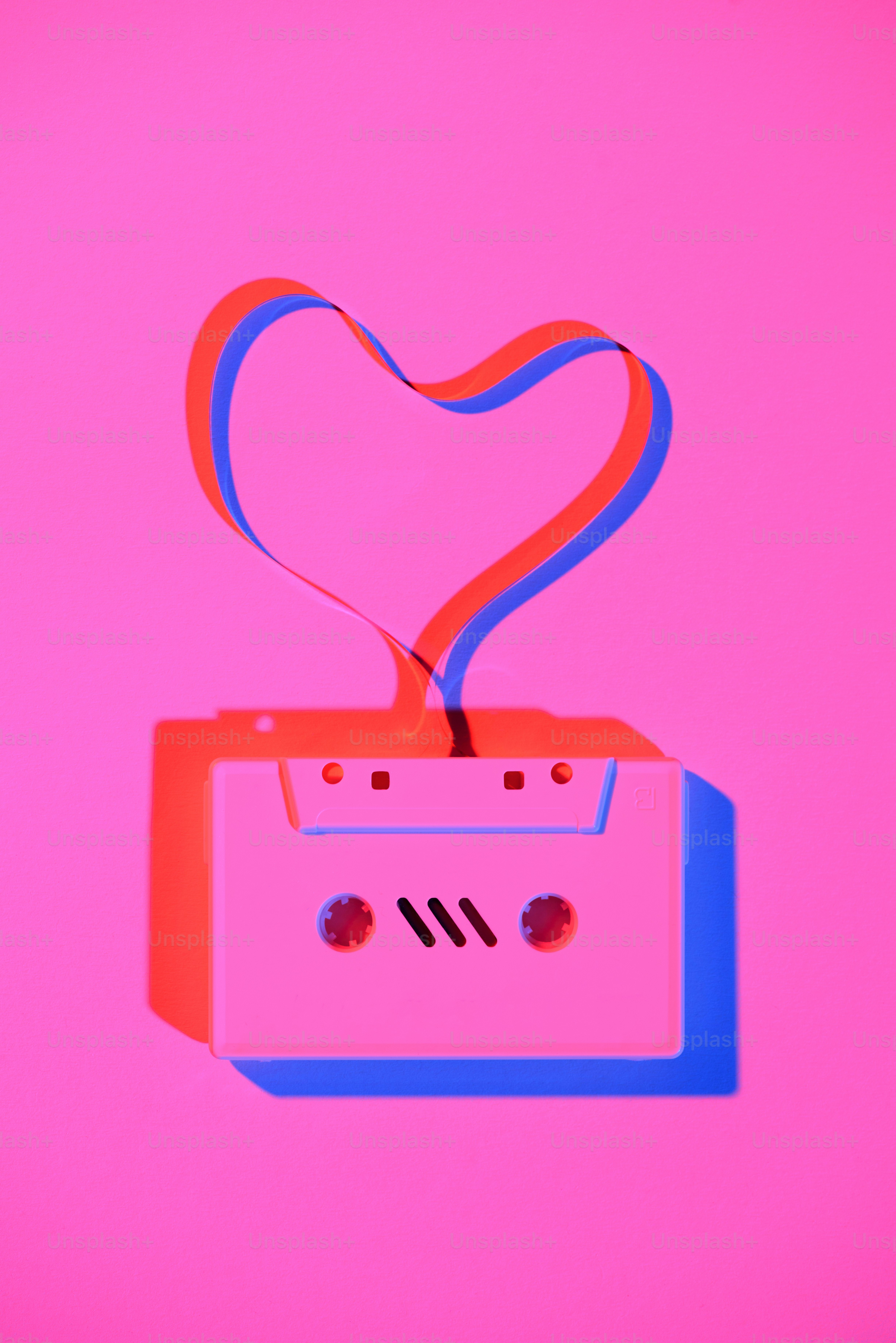 toned pink picture of retro audio cassette with tape in heart shape on tabletop