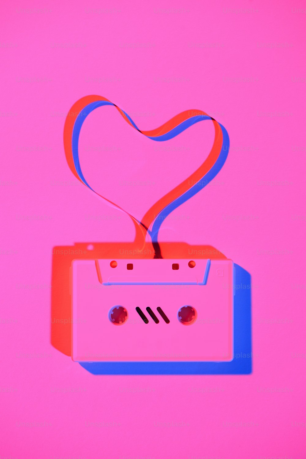 toned pink picture of retro audio cassette with tape in heart shape on tabletop